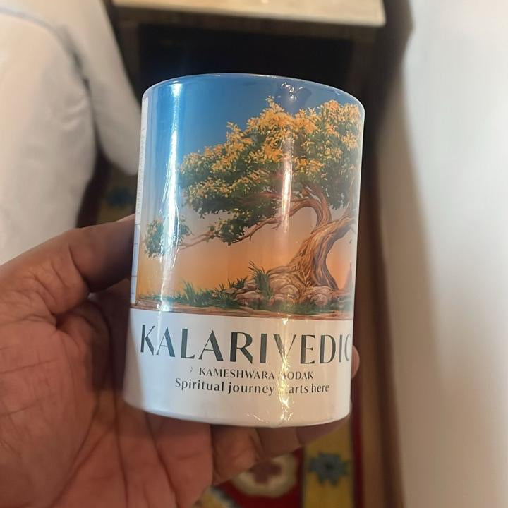 Hand holding a Kalarivedi tea canister with a blurred background
