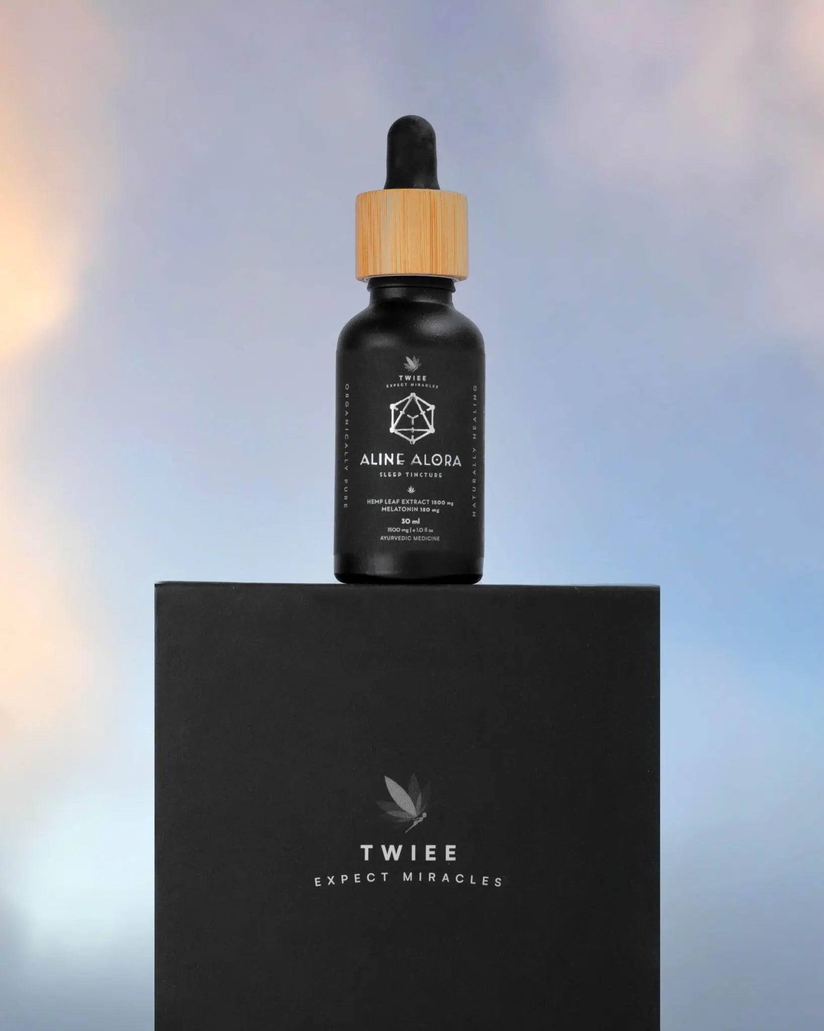 Twiee Aline Alora cannabis sleep tincture bottle on top of a black box with a blurred background.